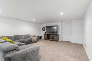 Spacious living area featuring neutral carpet flooring, recessed lighting, and white baseboards