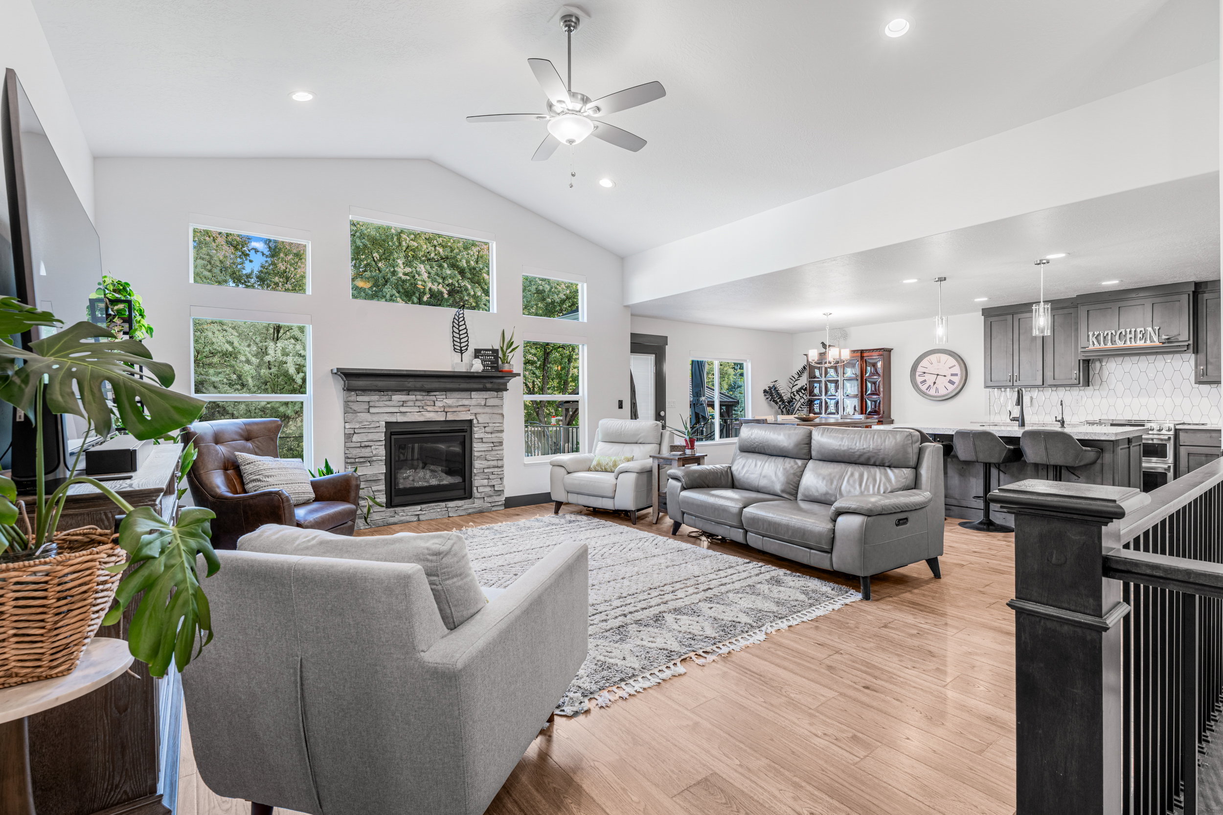 Vaulted living room with a stone-clad fireplace and wood-finish flooring