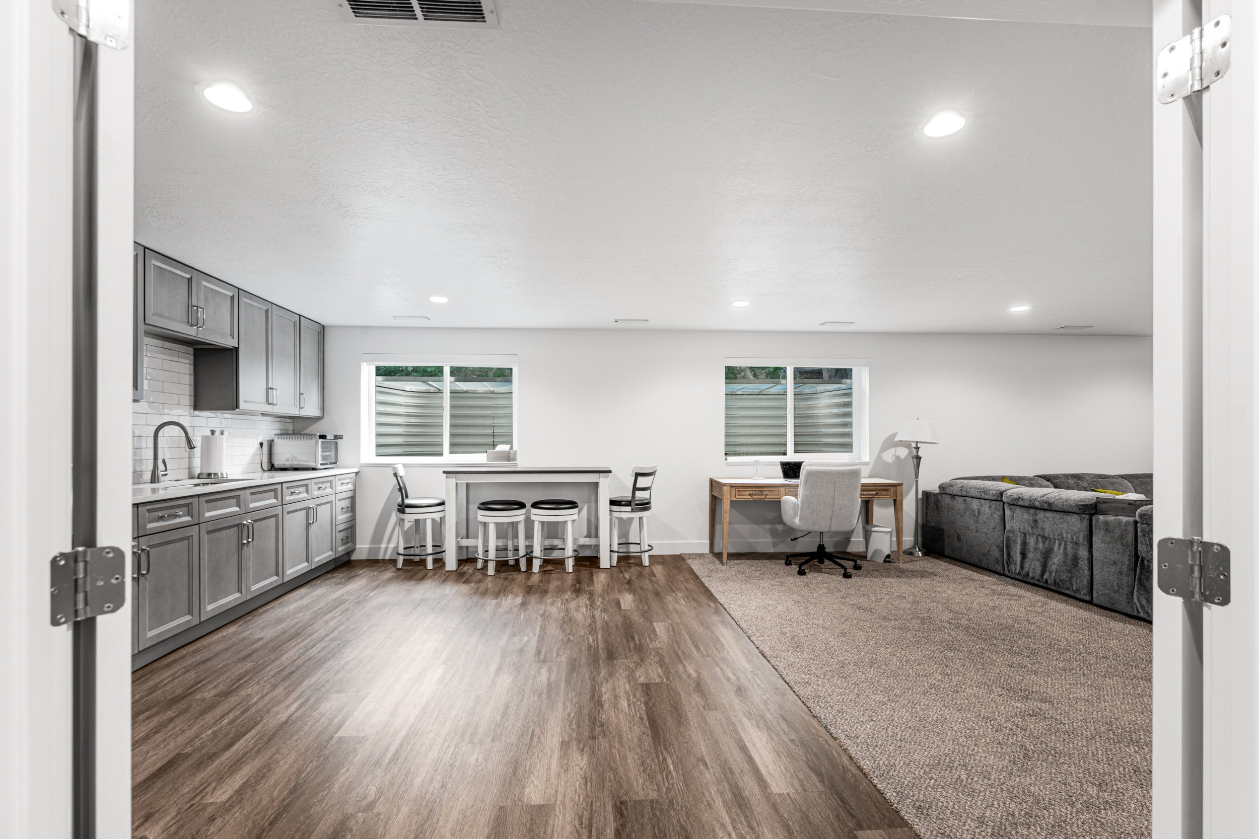 Open-concept living space featuring wood-finish flooring, recessed lighting, and a full kitchen with gray cabinetry