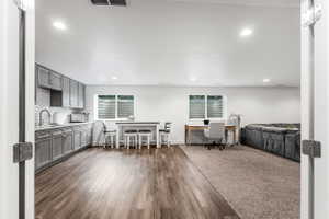 Open-concept living space featuring wood-finish flooring, recessed lighting, and a full kitchen with gray cabinetry