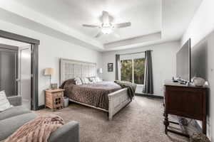 Spacious room featuring a decorative headboard, tray ceiling, recessed lighting, and a ceiling fan