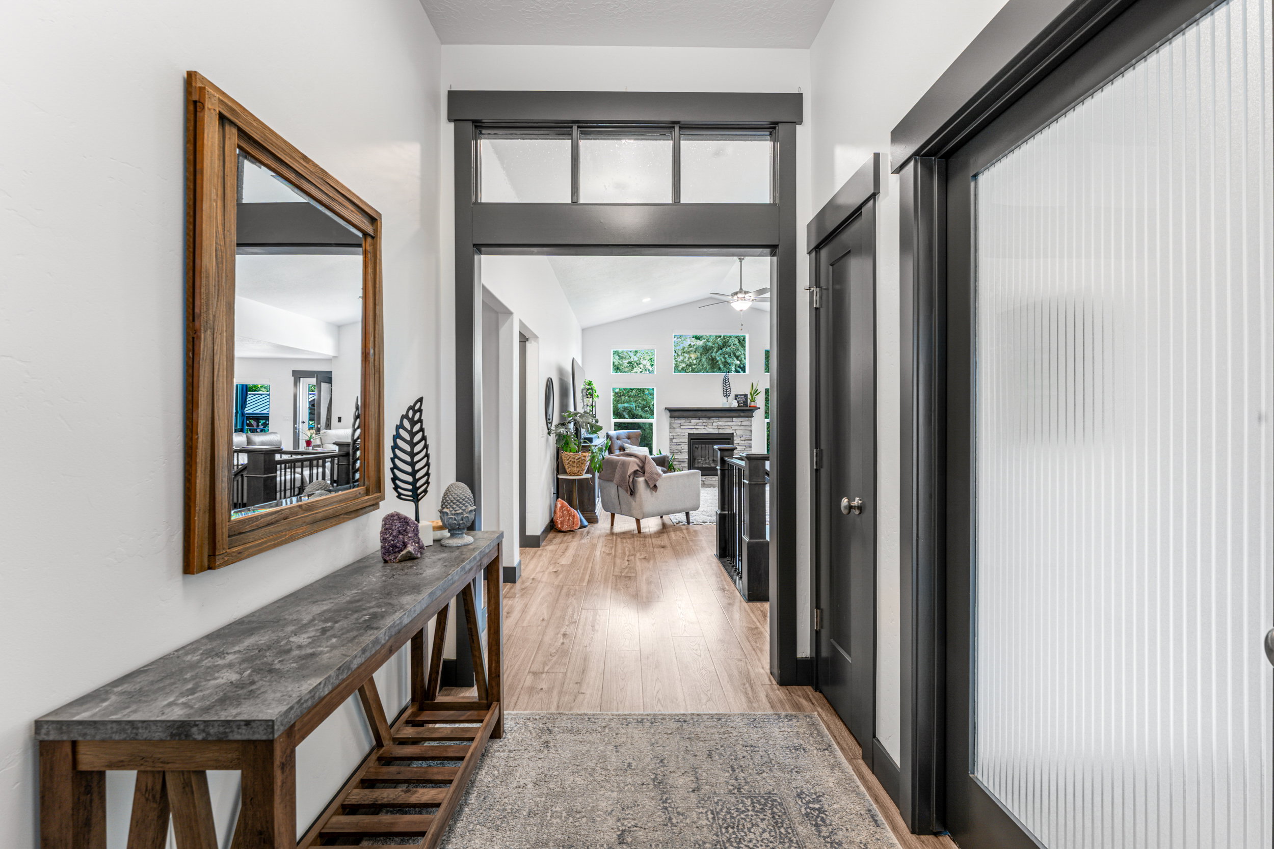 Entryway featuring wood-finish flooring, dark trim accents, and a textured glass door