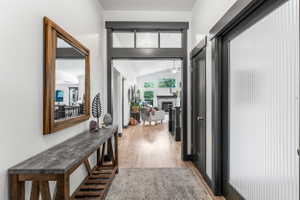 Entryway featuring wood-finish flooring, dark trim accents, and a textured glass door