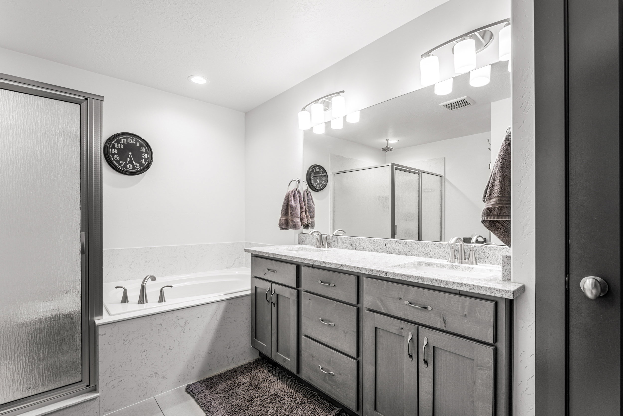 Double vanity with undermount sinks, stone countertop, and contemporary lighting fixtures