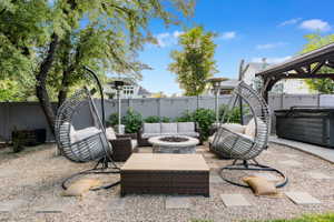 Landscaped backyard featuring a central fire pit, stone pavers, and a gravel surface