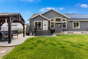 Spacious backyard featuring a manicured lawn, a large concrete patio with an adjacent wood pergola, and a multi-level deck with dark composite steps