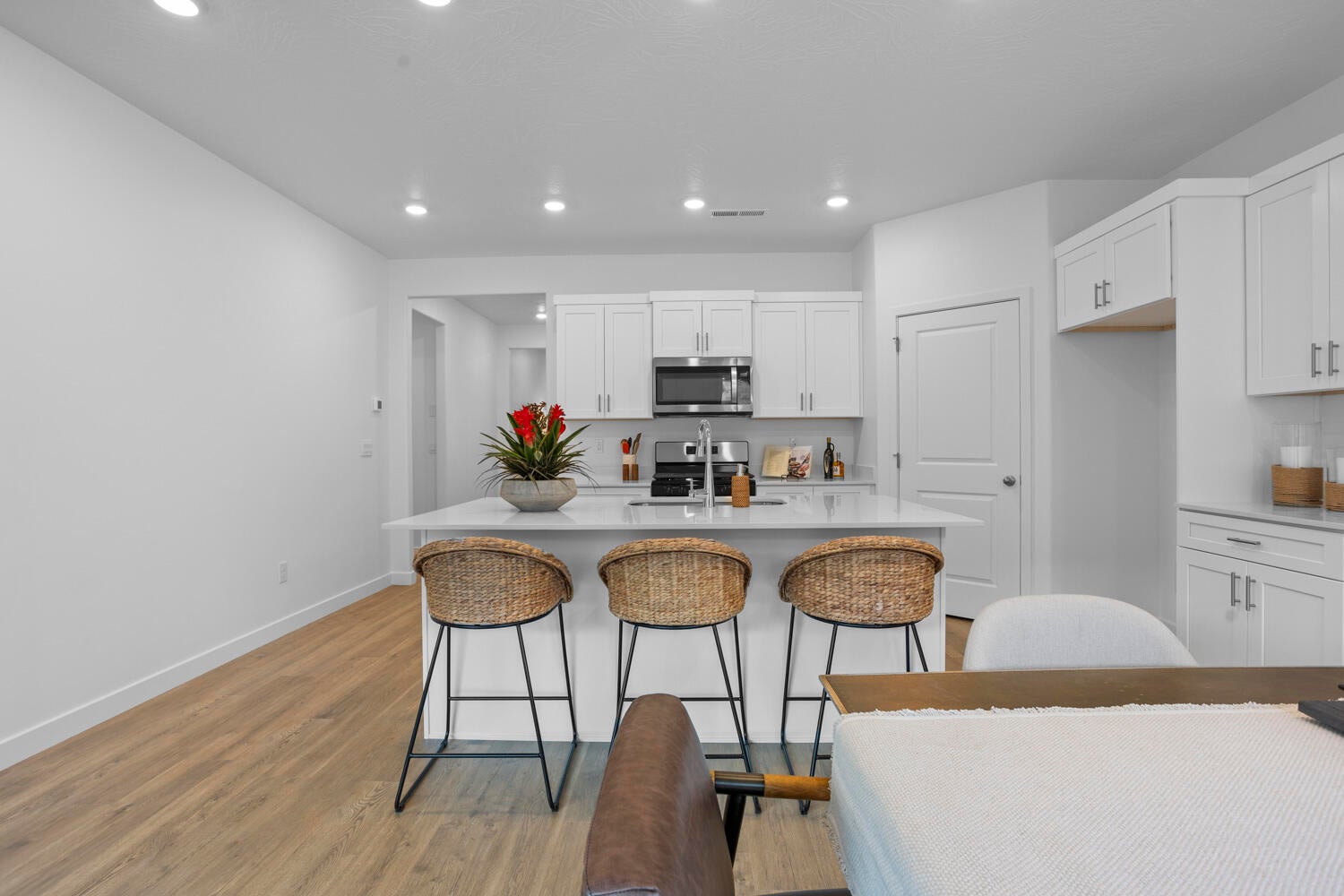 Modern kitchen featuring white cabinetry, stainless steel appliances, a white island with seating, and wood-finish flooring
