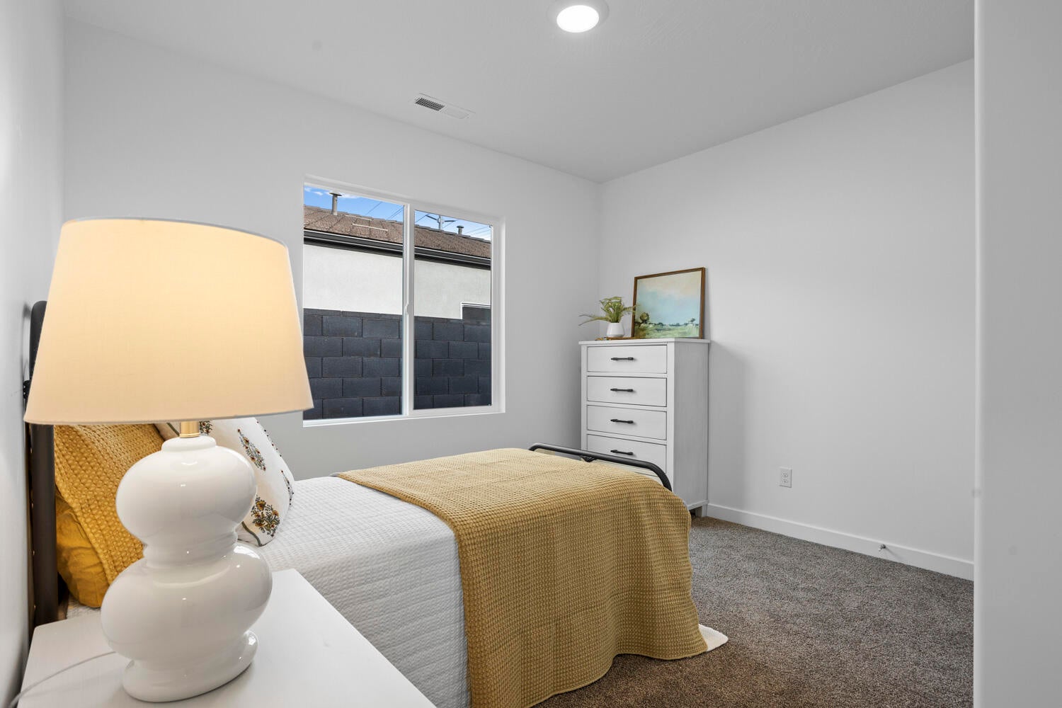 Bedroom featuring light gray wall paint, a single window with a black-framed exterior, recessed ceiling lighting, and dark gray carpet flooring