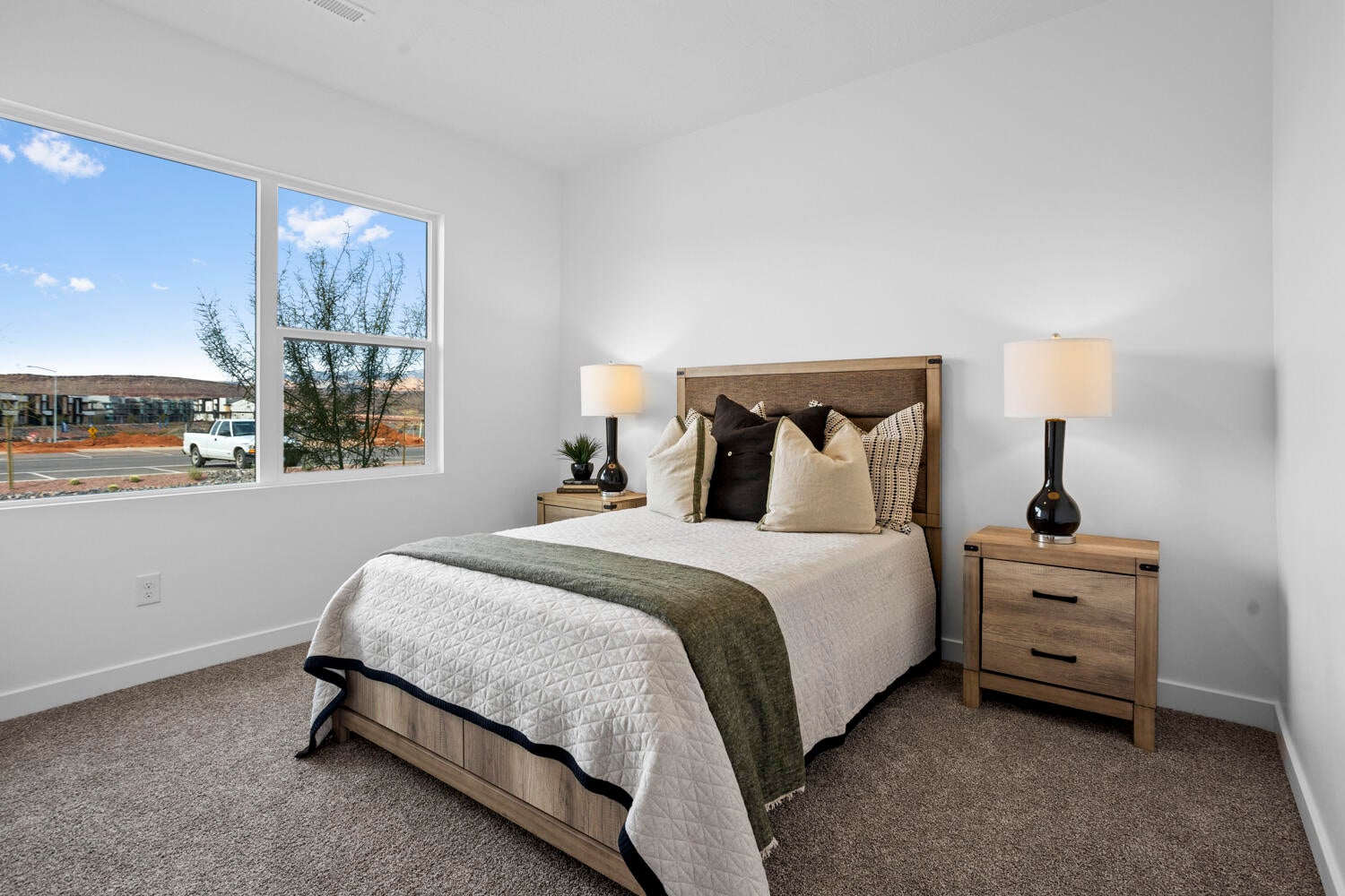 Bedroom featuring a large window, neutral carpeting, white walls, light wood-finish bed frame, and coordinating nightstands