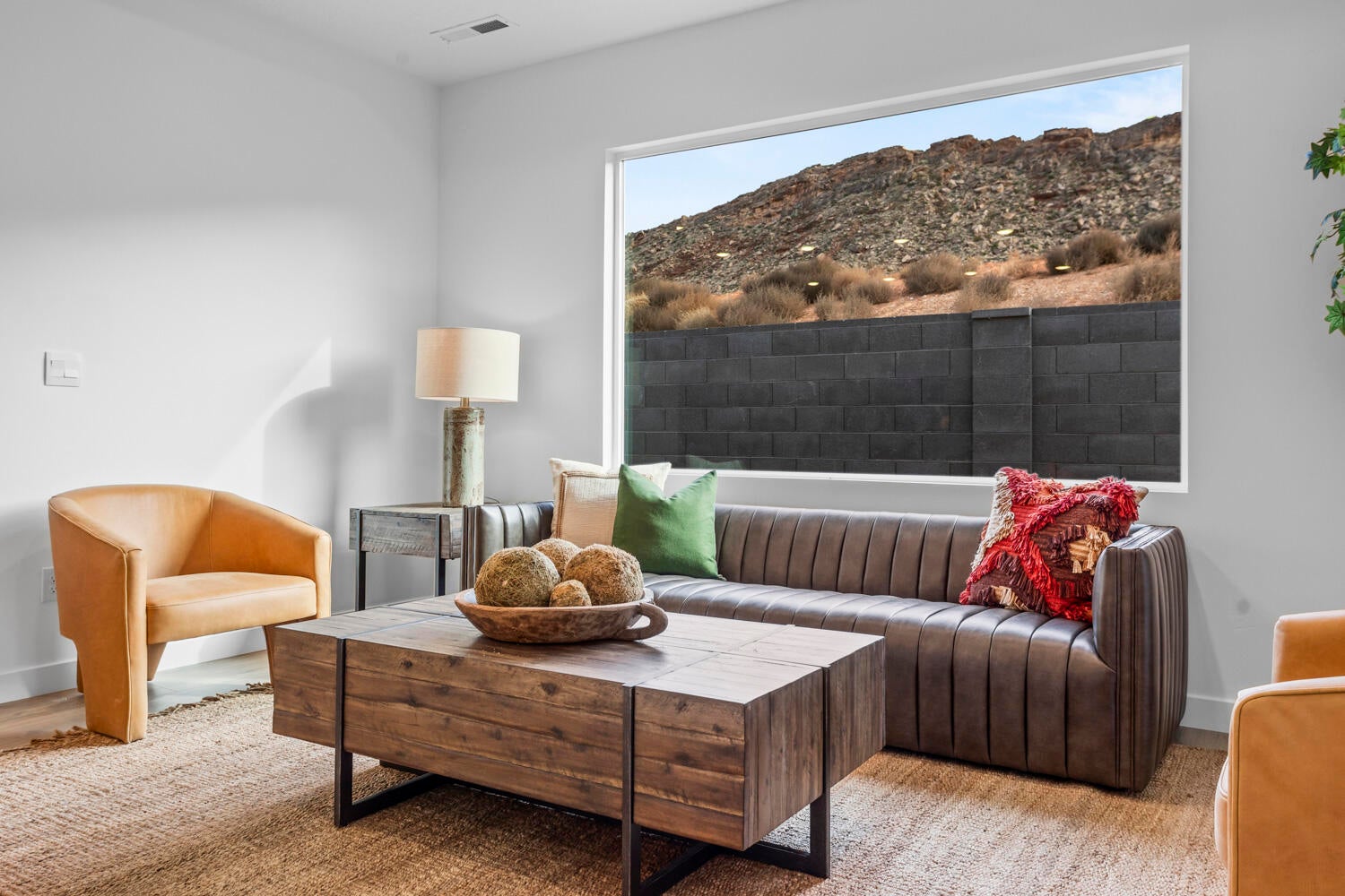 Spacious living area featuring a large horizontal picture window, wood-finish flooring, and crisp white walls