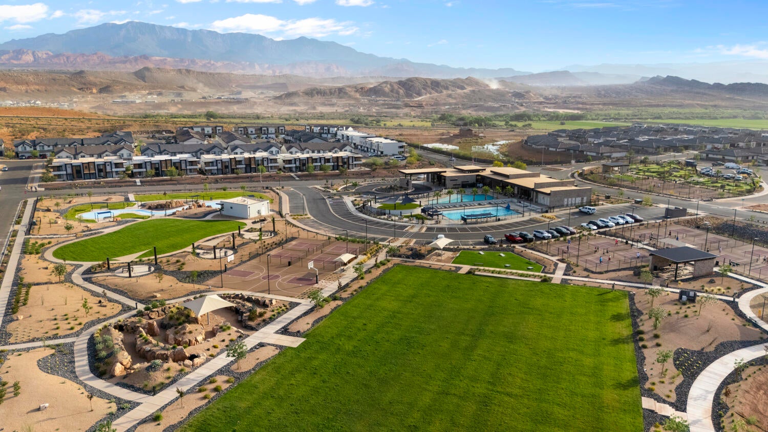 Expansive community grounds featuring a large green space, a multi-court sports area, and a structured play area