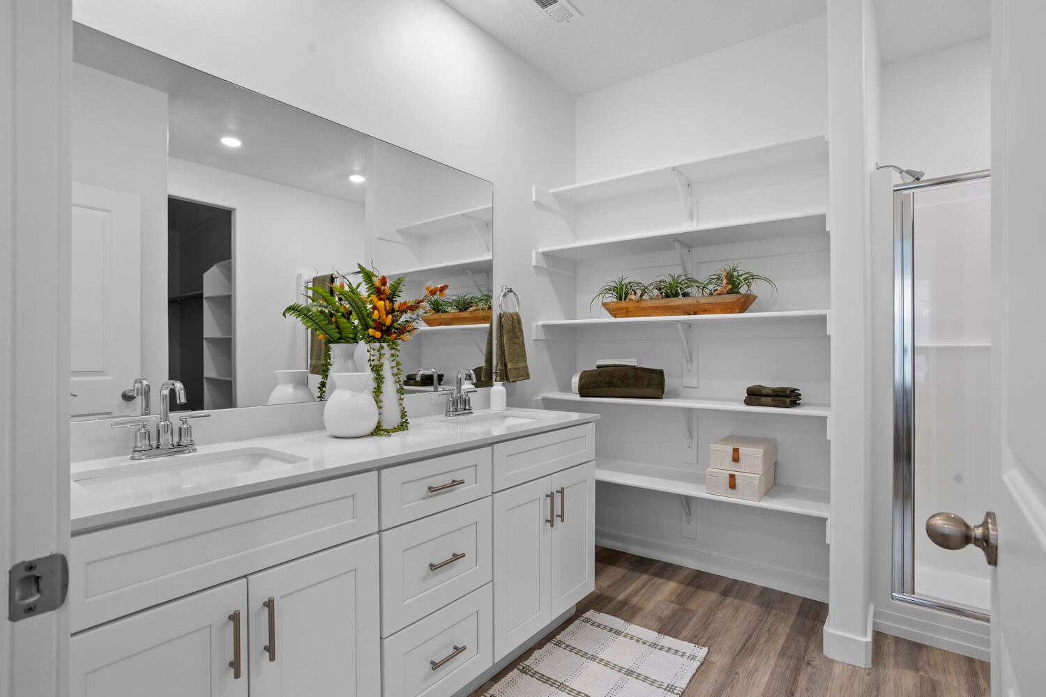 Contemporary bathroom featuring dual white vanities with integrated sinks and a large frameless mirror