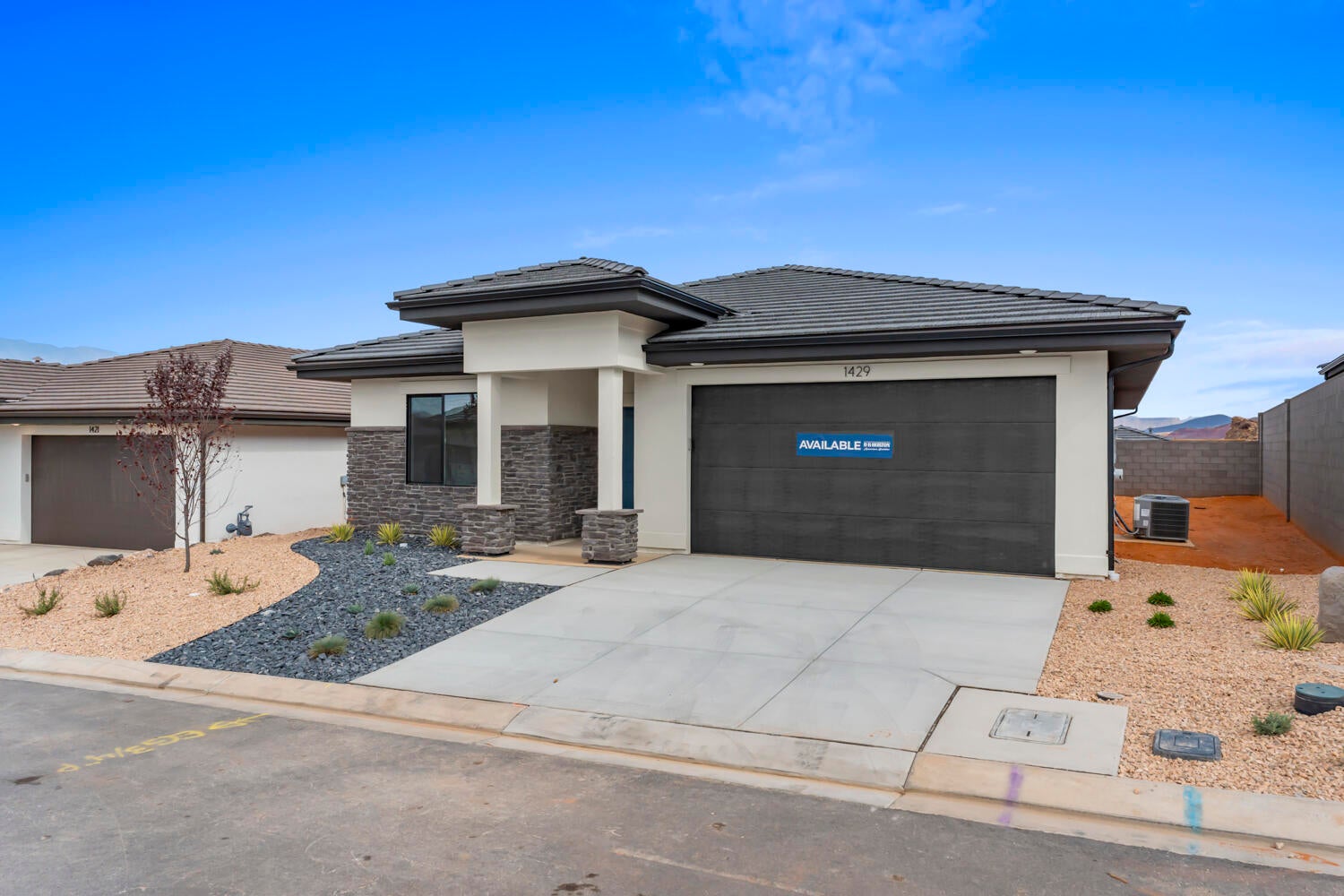 Contemporary exterior featuring a split-level roofline, stone veneer accents, and a dark garage door