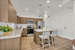 Modern kitchen featuring wood-finish cabinetry, light-toned granite countertops, and a white subway tile backsplash