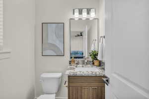 Bathroom vanity featuring a light-toned granite countertop, undermount sink, and wood-finish cabinetry