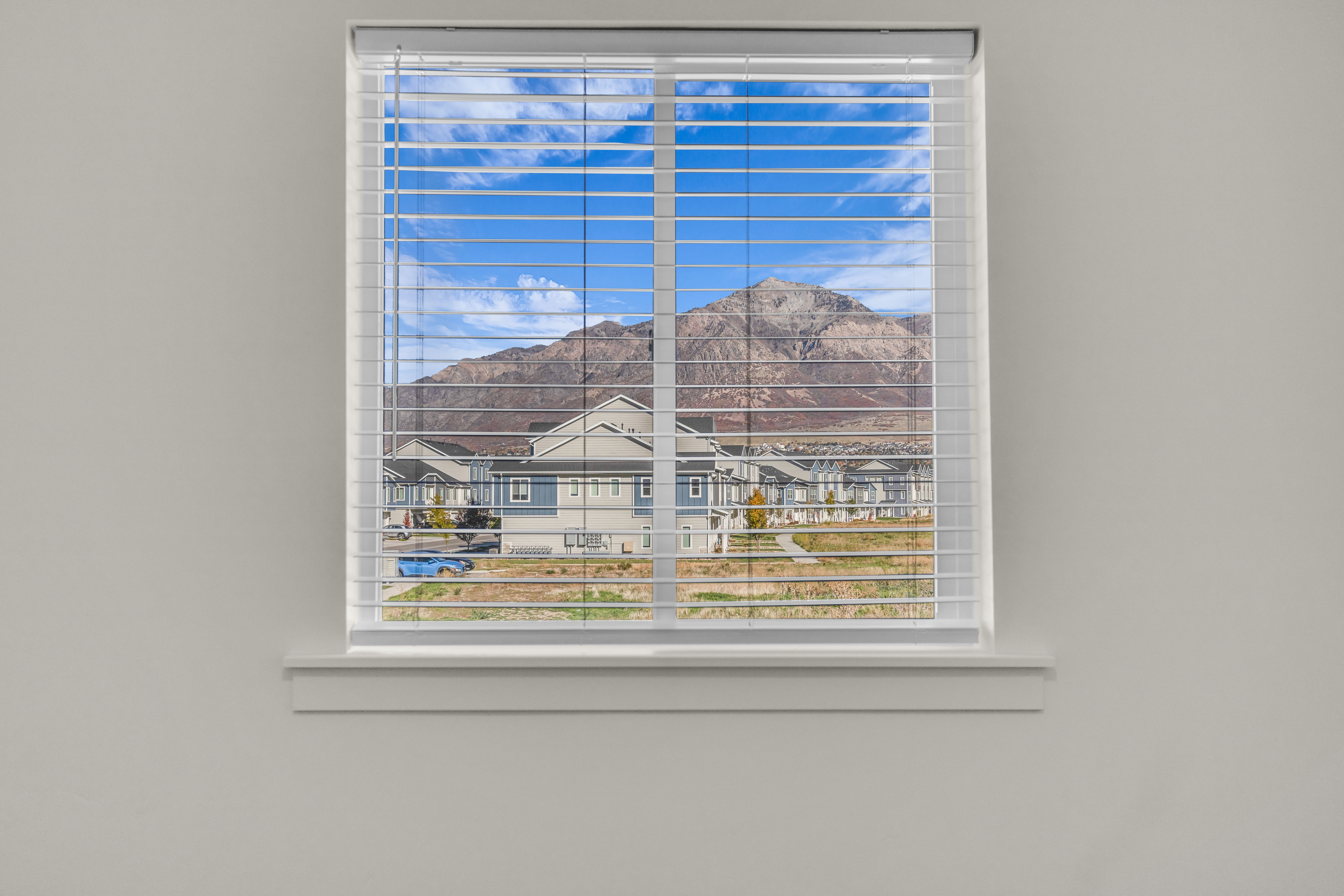 White-framed window featuring horizontal blinds