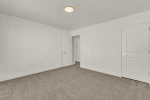 Spacious room featuring neutral carpeting, white walls, and bright white trim