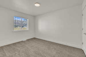 Spacious room with plush carpet flooring, white walls, and a large window with white blinds
