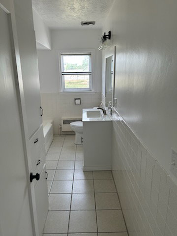 Ceramic tile flooring features in this bathroom, complemented by white wall tile wainscoting