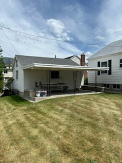 Rear exterior featuring a covered concrete patio, white siding, and a dark shingle roof