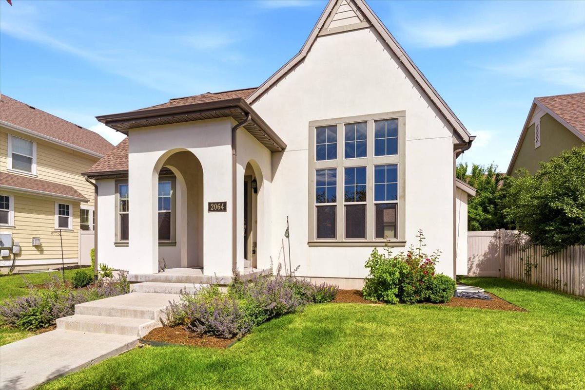 White stucco exterior featuring a prominent arched entry and a large multi-pane window