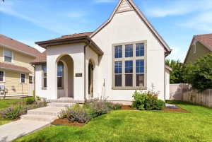 White stucco exterior featuring a prominent arched entry and a large multi-pane window