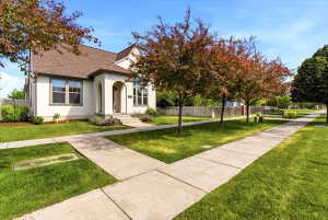 Charming stucco exterior with arched entry, gabled roofline, and mature landscaping
