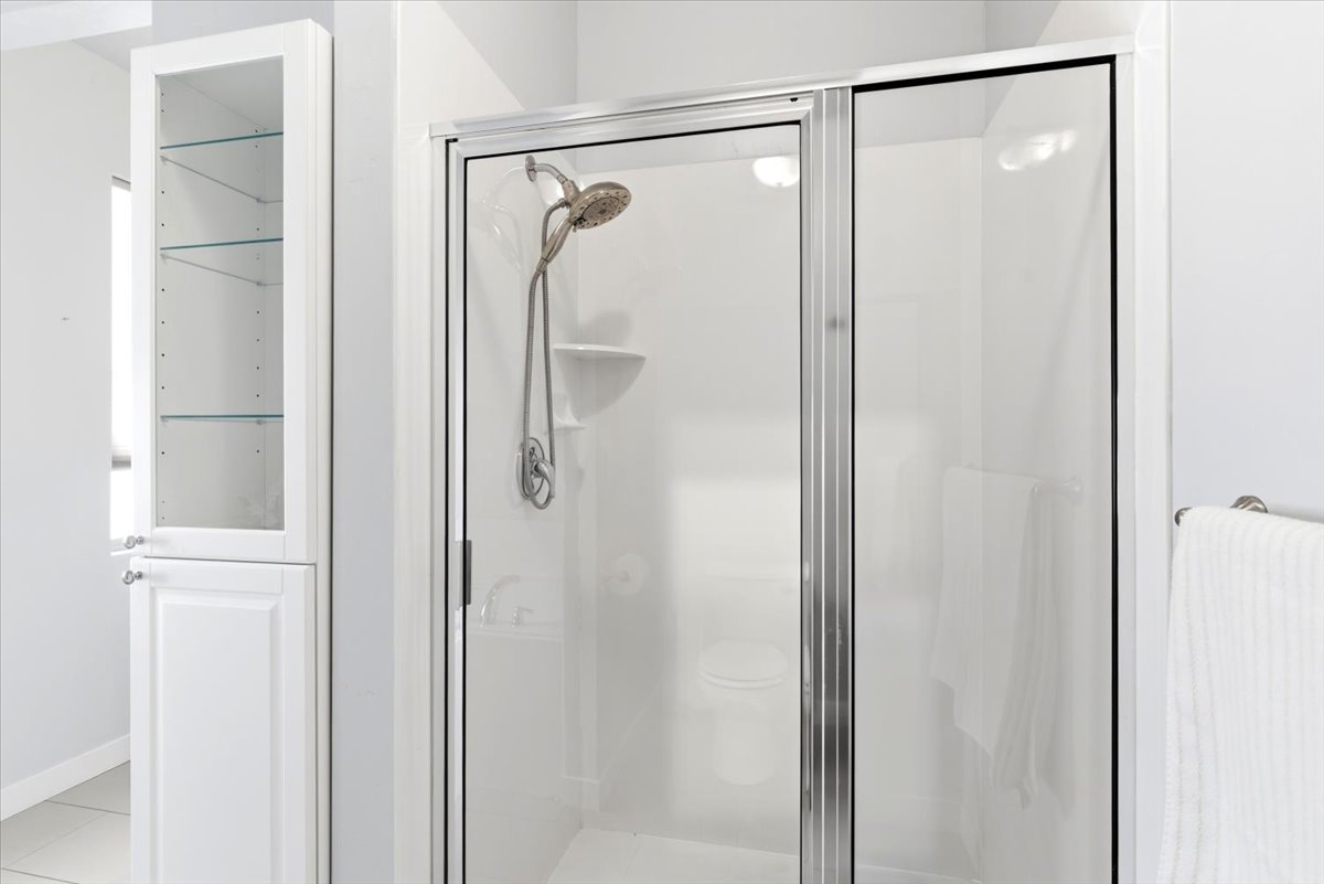 Enclosed shower with a brushed nickel showerhead and a built-in shelf