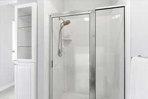 Enclosed shower with a brushed nickel showerhead and a built-in shelf
