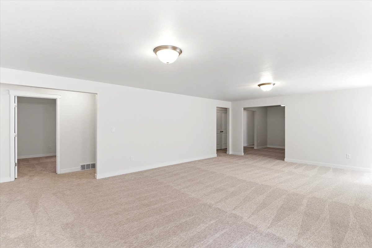 Spacious room featuring neutral carpeting, white walls, and two ceiling-mounted dome light fixtures