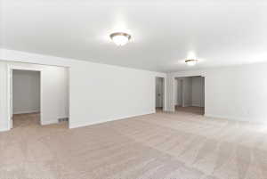 Spacious room featuring neutral carpeting, white walls, and two ceiling-mounted dome light fixtures