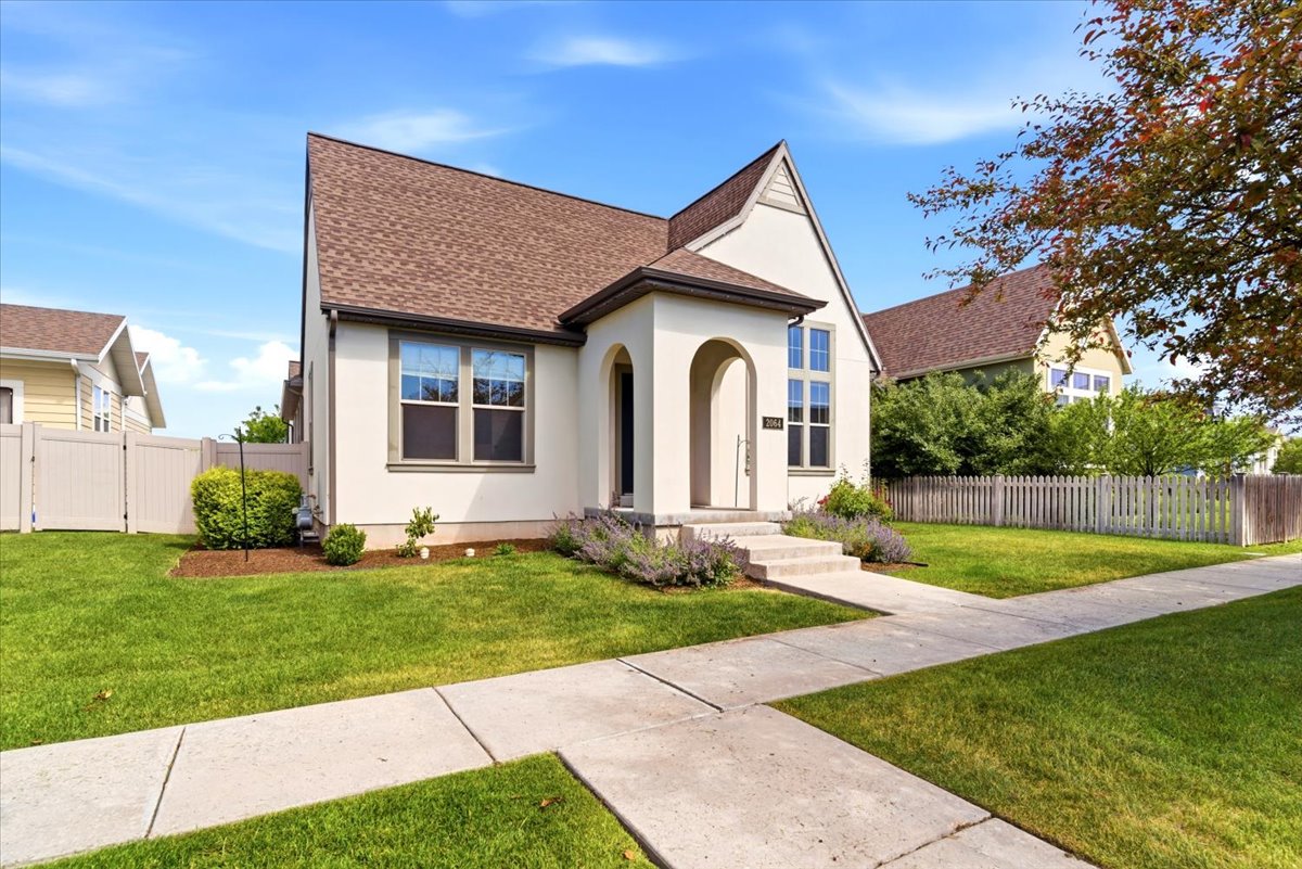 Stucco exterior with a peaked roofline, arched entry, and dark window trim