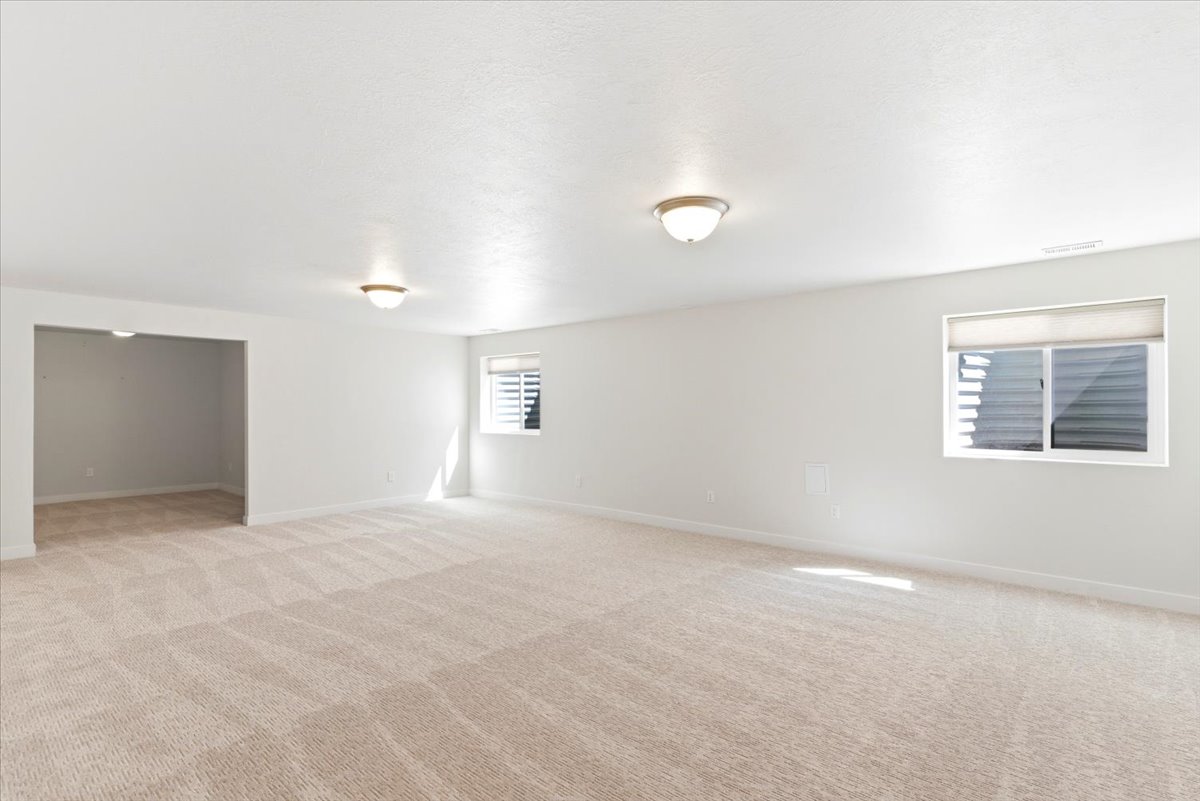 Spacious room with light-colored patterned carpeting, white walls, and two flush-mount ceiling lights