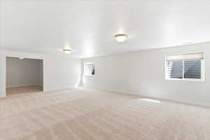 Spacious room with light-colored patterned carpeting, white walls, and two flush-mount ceiling lights