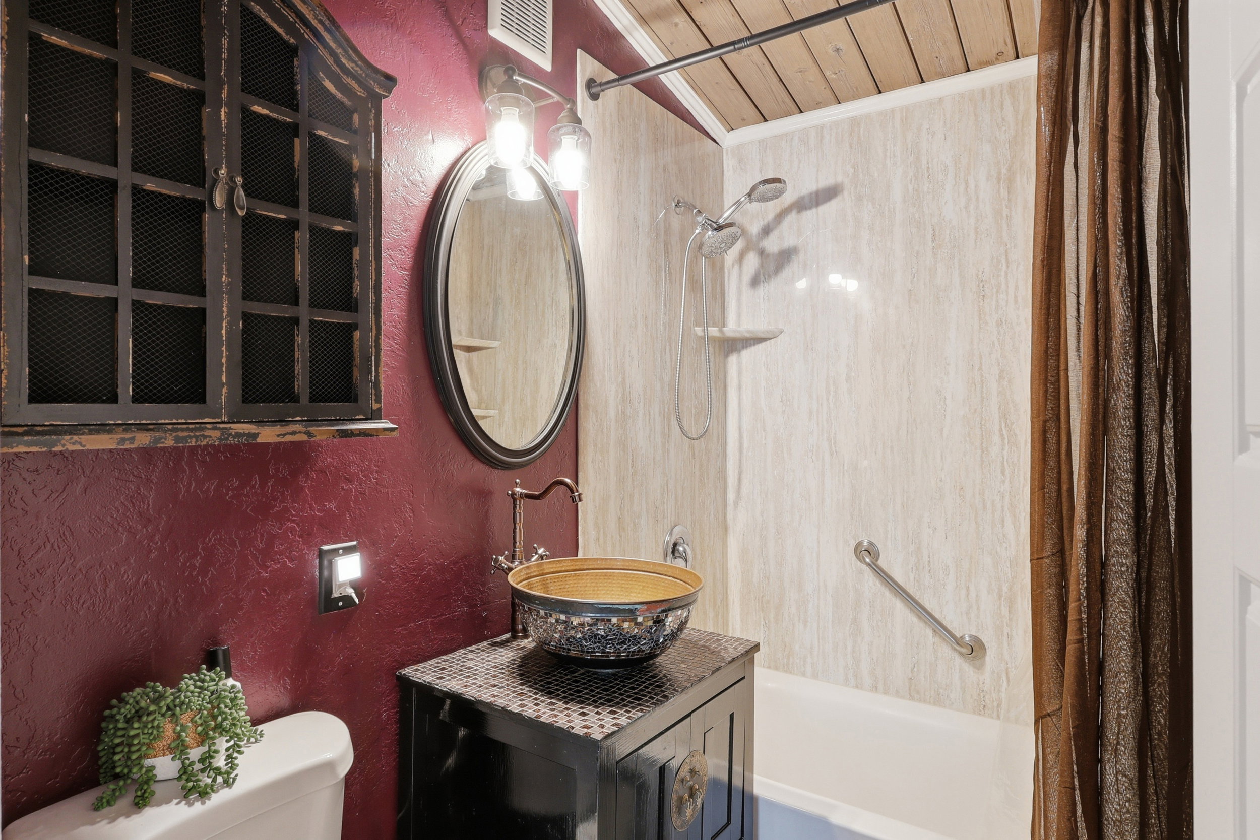 Bathroom featuring a vessel sink atop a dark vanity, a full tub with shower fixture, and a wall-mounted medicine cabinet