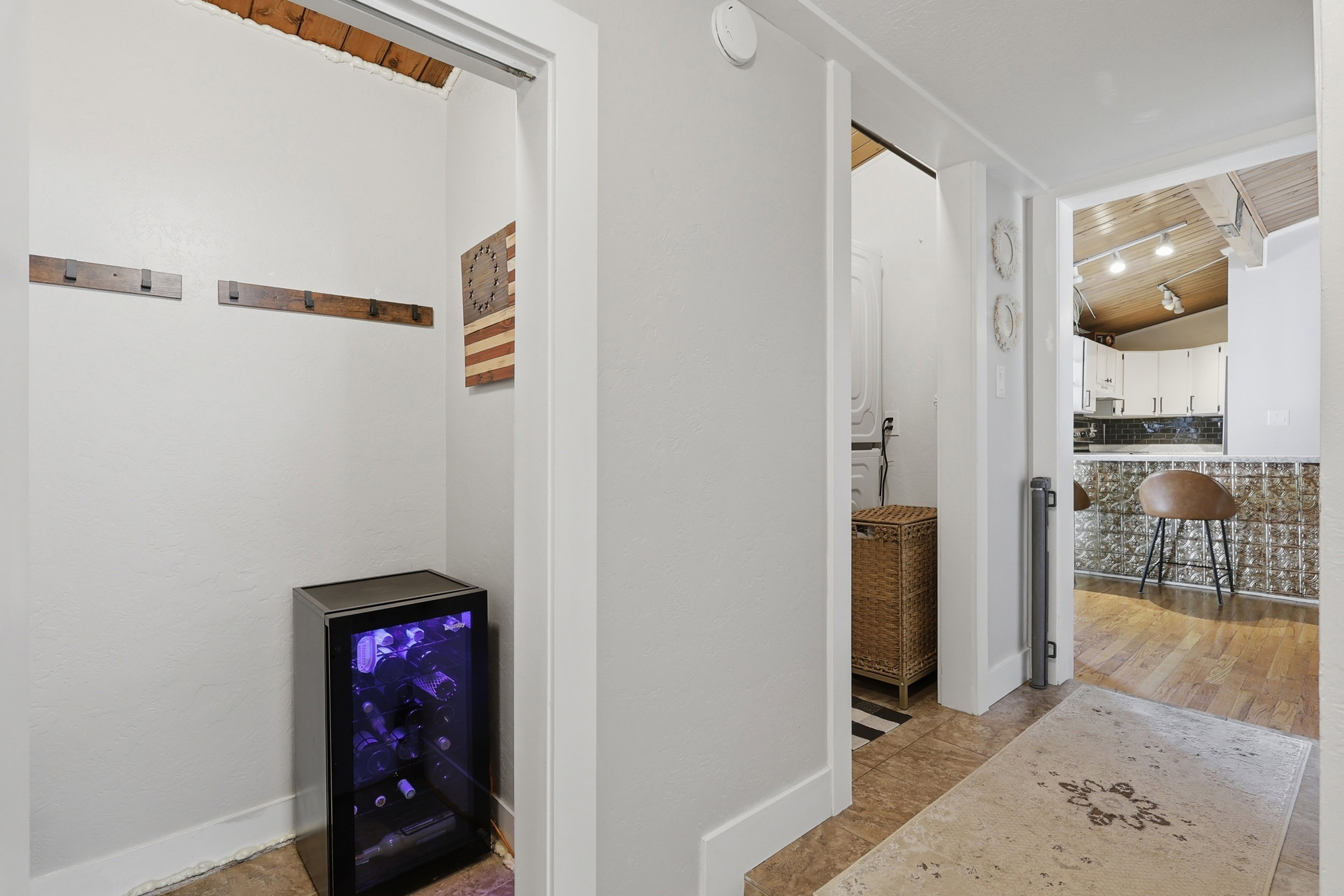 Recessed alcove with built-in wine refrigerator and wooden coat hooks
