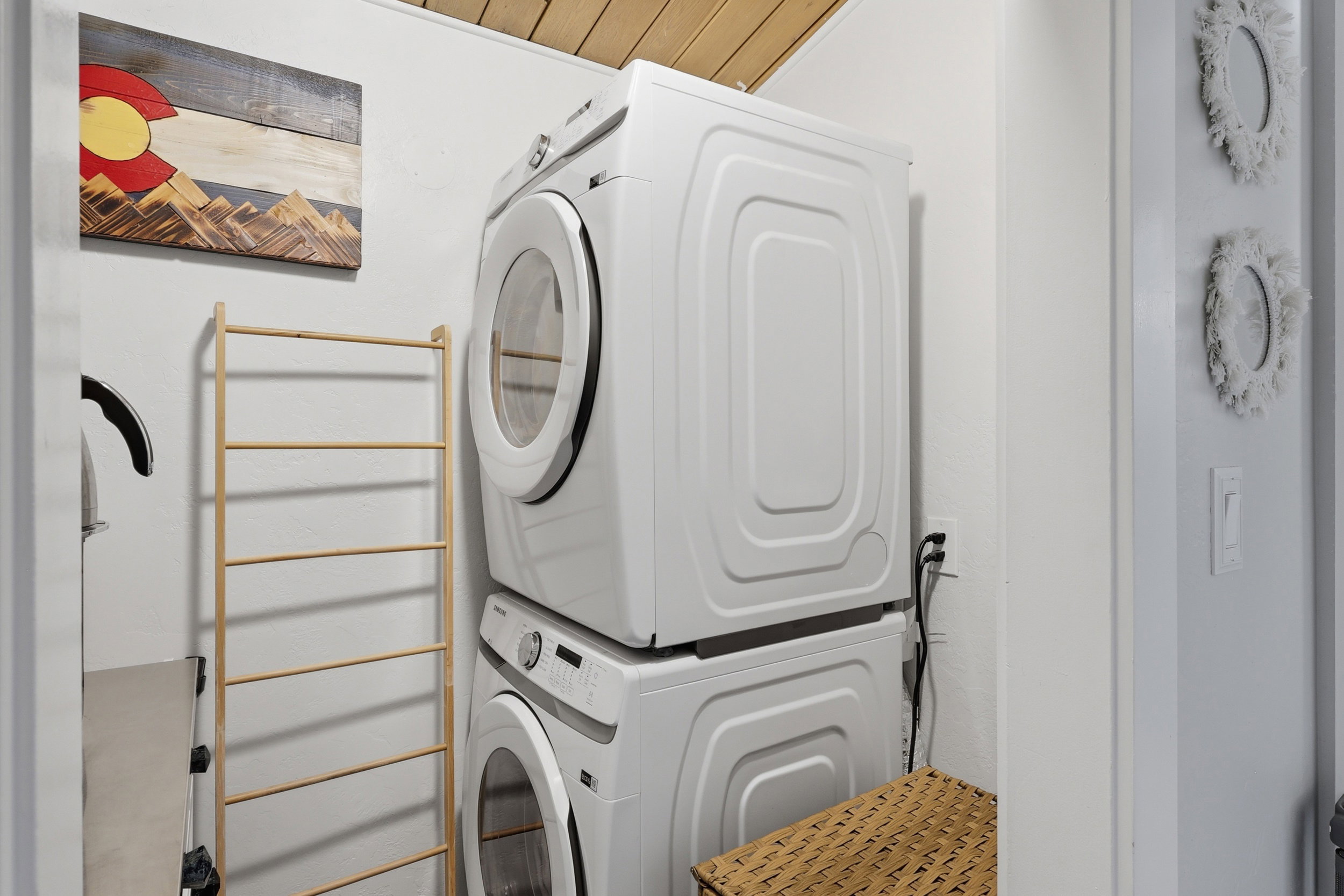 Dedicated laundry area featuring a stacked washer and dryer, wood-panel ceiling, and white walls