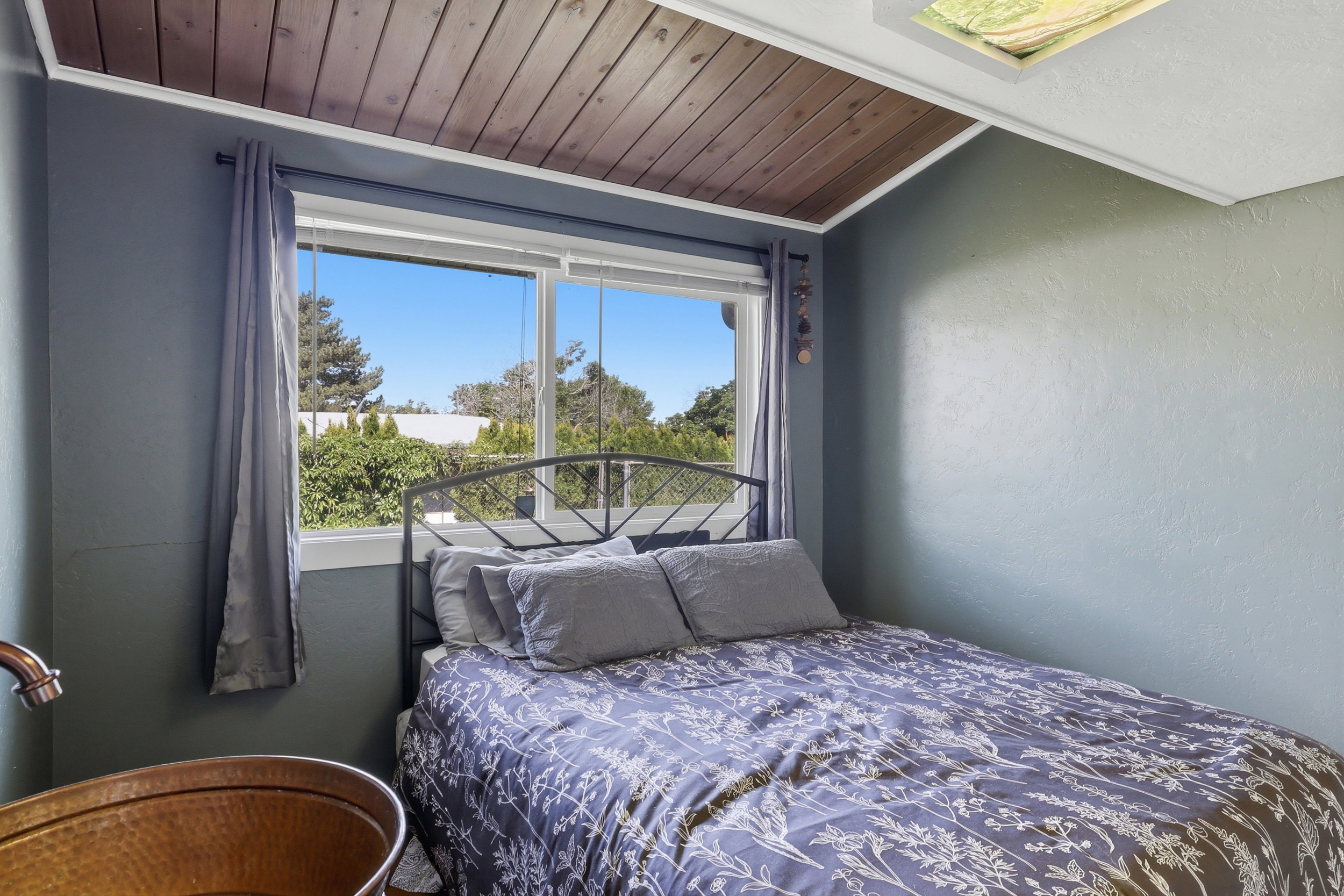 Interior space featuring a wood-panel ceiling and a rectangular window with white trim