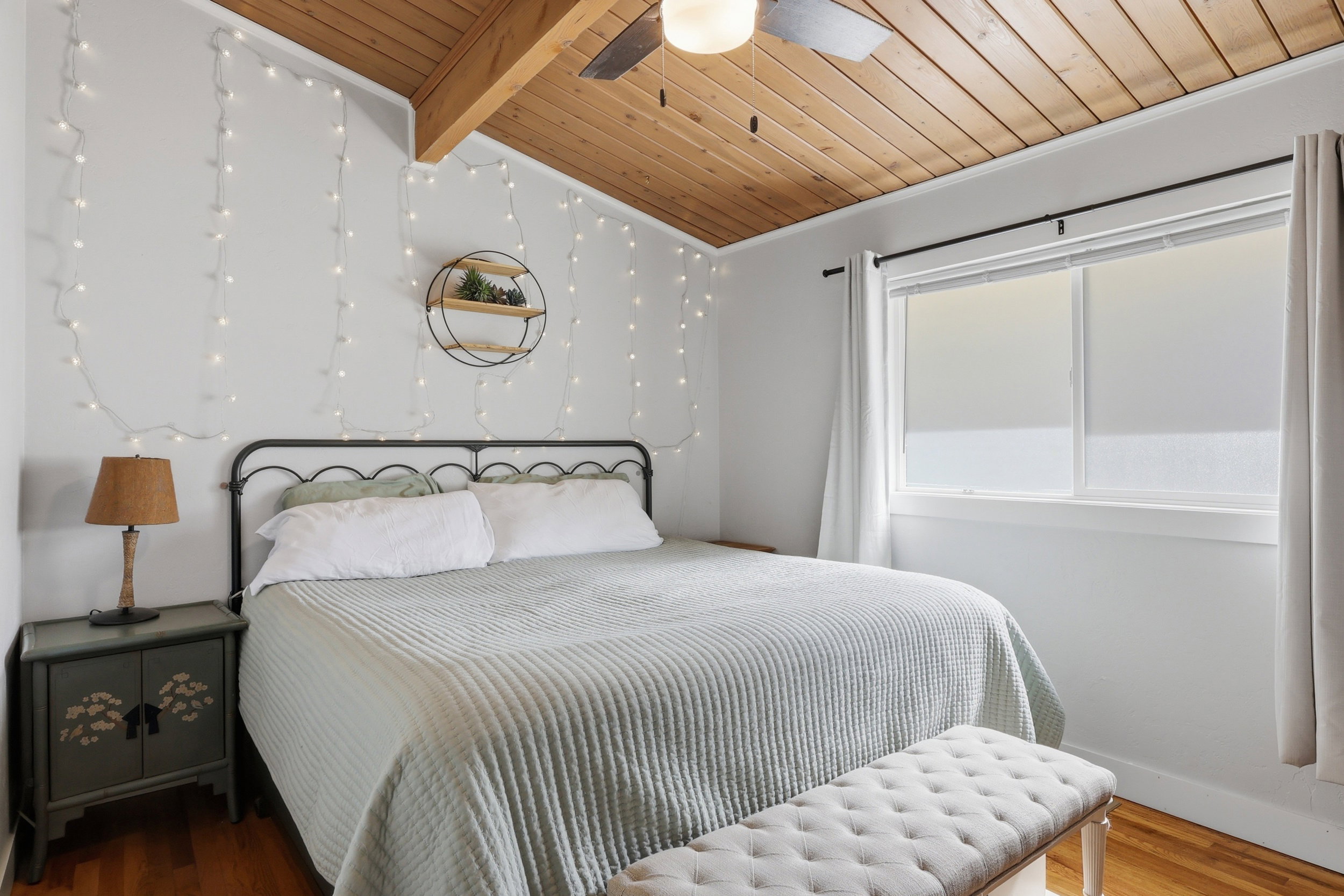 Bedroom featuring wood-finish flooring, a sloped wood-paneled ceiling with an exposed beam, and a ceiling fan with integrated lighting
