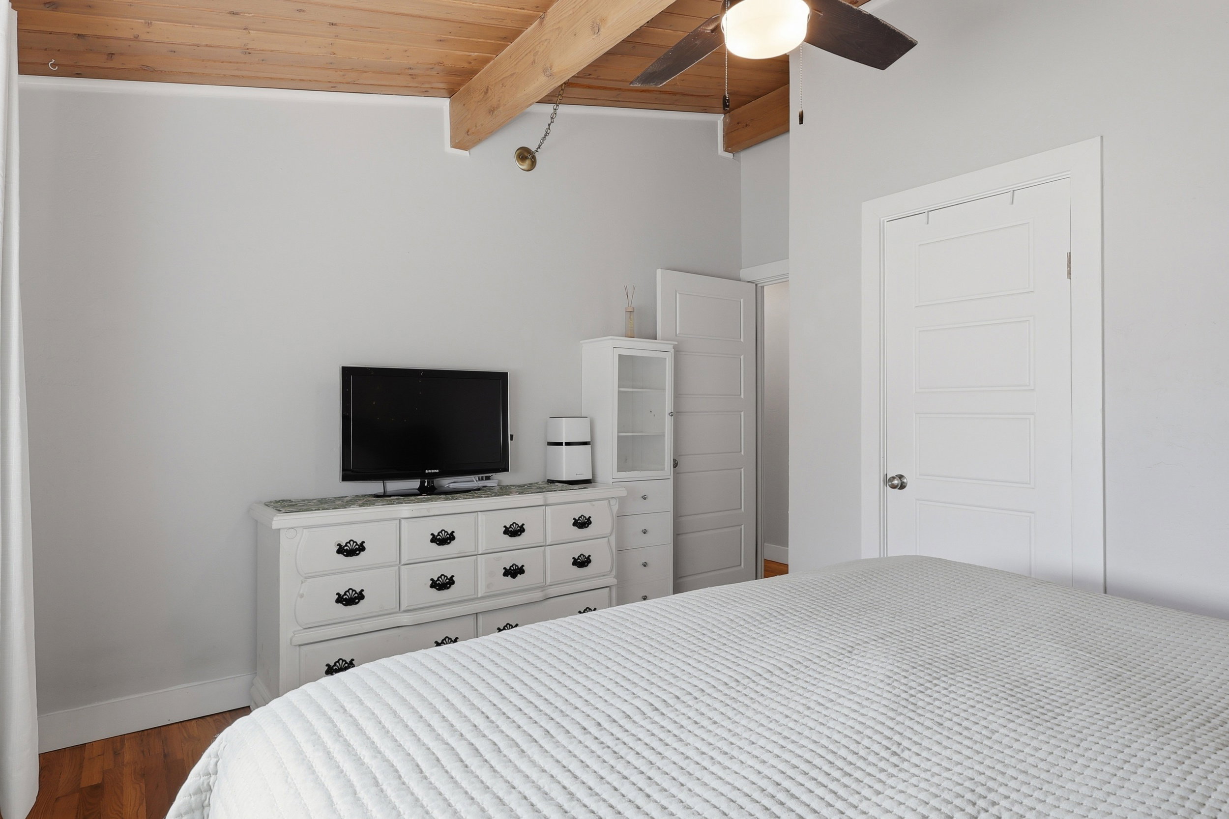 Vaulted wood-finish ceiling with exposed beams and a ceiling fan