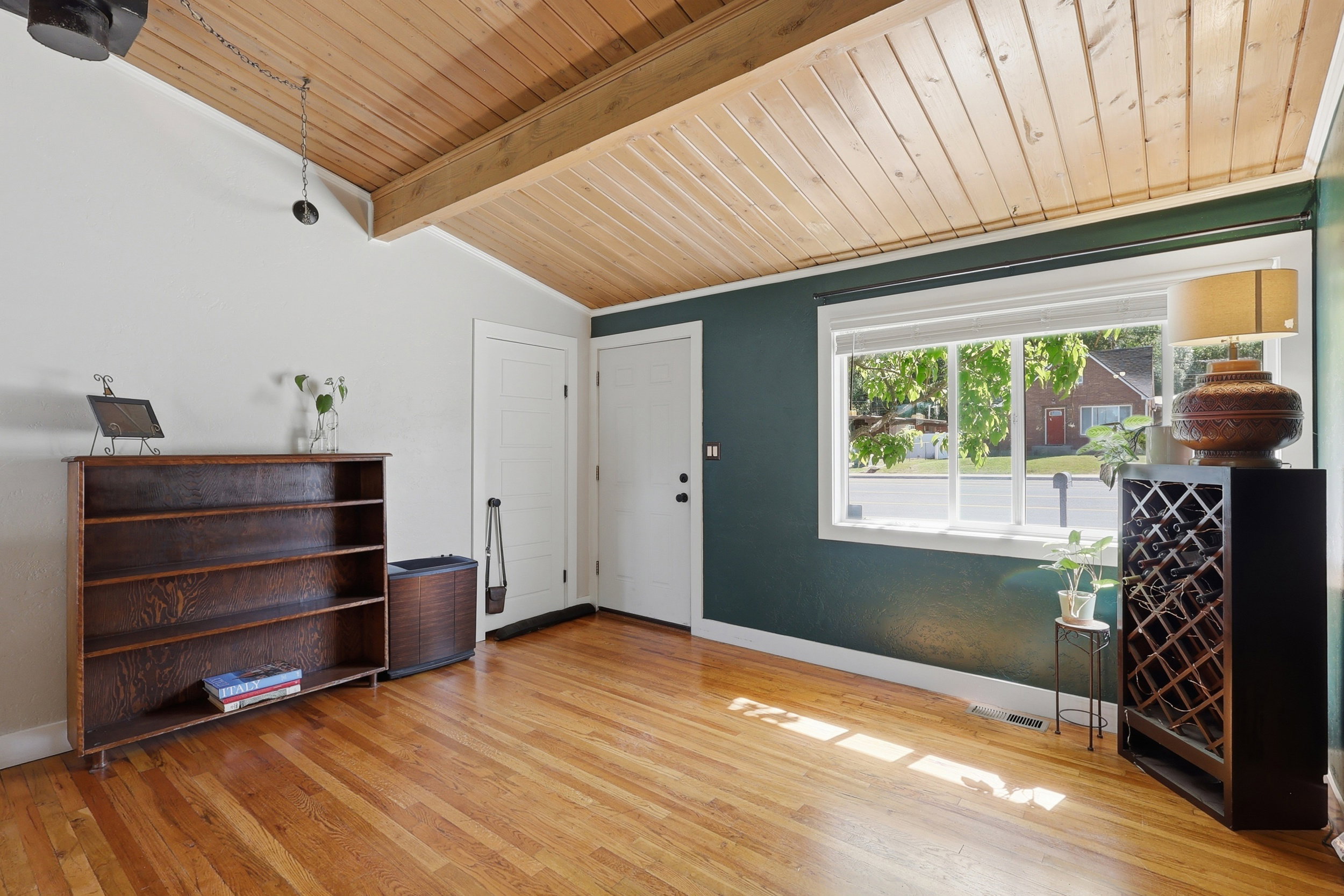 Hardwood flooring extends throughout this room, featuring a vaulted ceiling with natural wood paneling and exposed beams