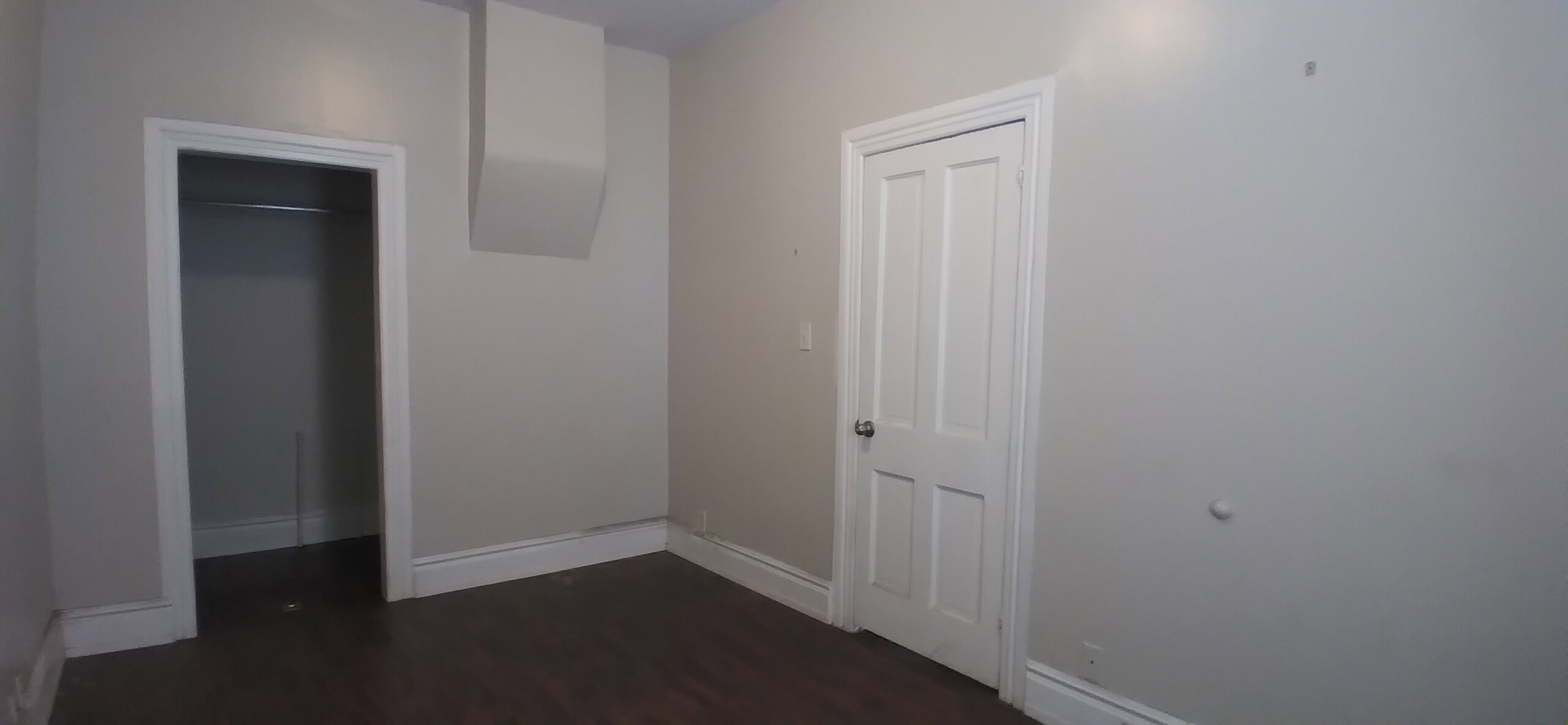 Room featuring dark wood-finish flooring, light neutral-toned walls, and white trim