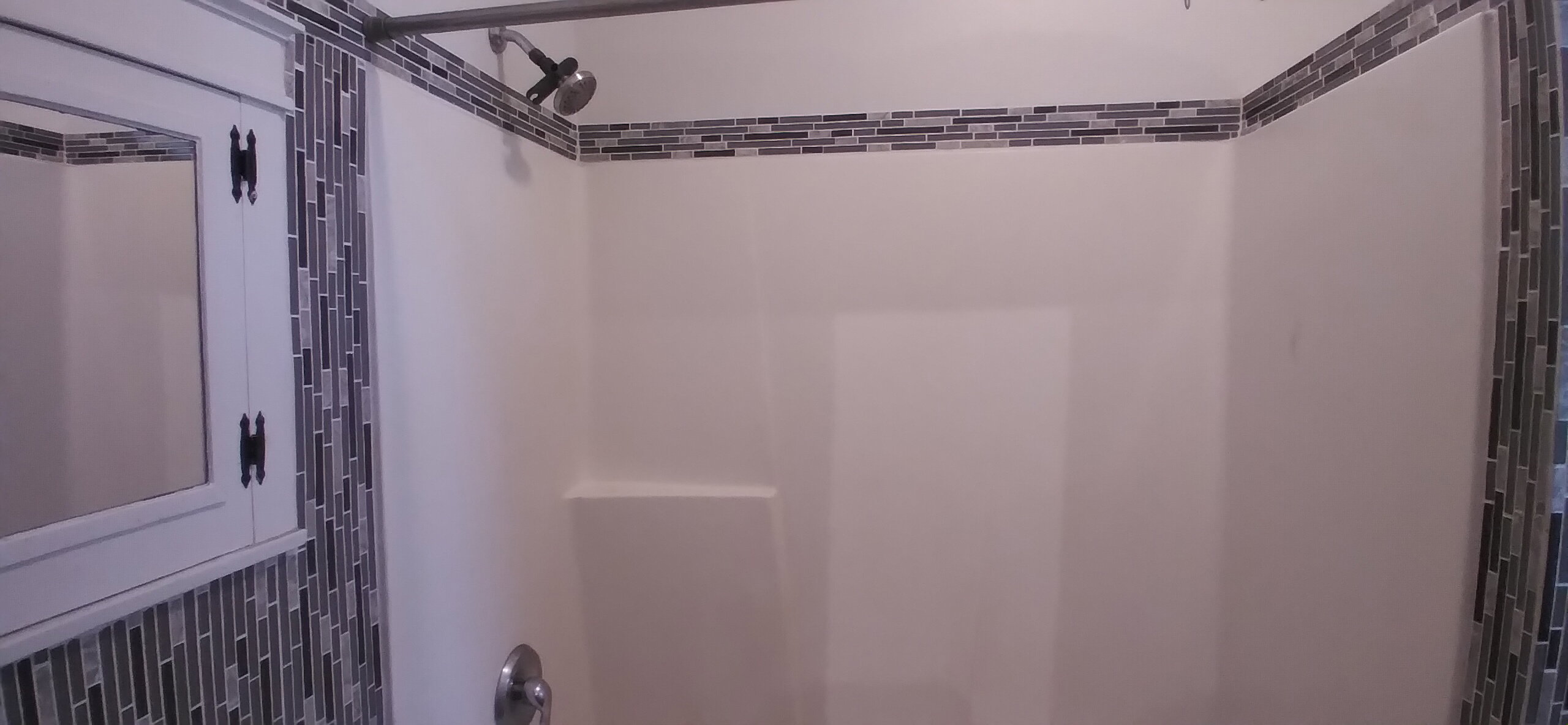 Shower with mosaic tile accents, integrated soap ledge, and chrome fixtures