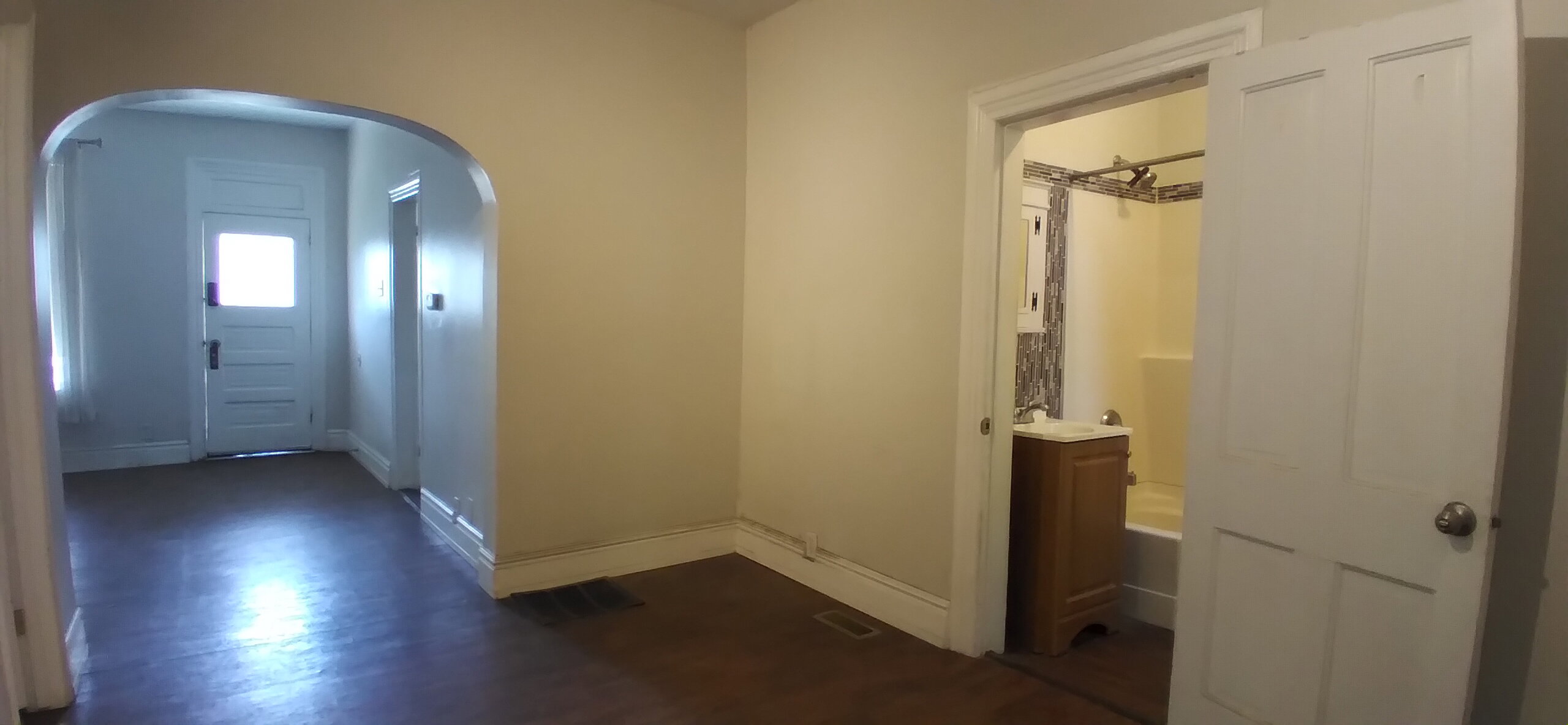 Archway entrance to additional room with white paneled door and natural light
