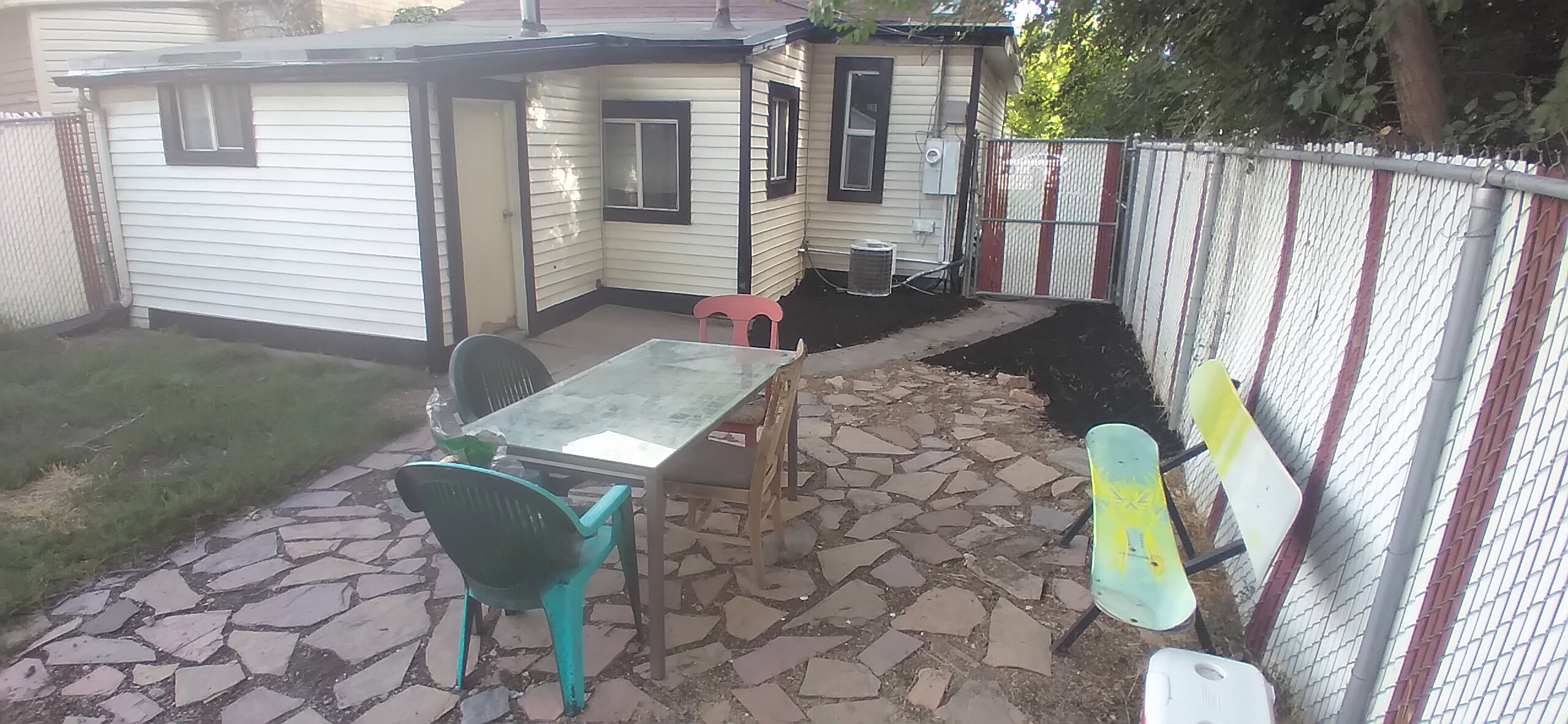 Paved patio area featuring irregular stone pavers, surrounded by a chain-link fence
