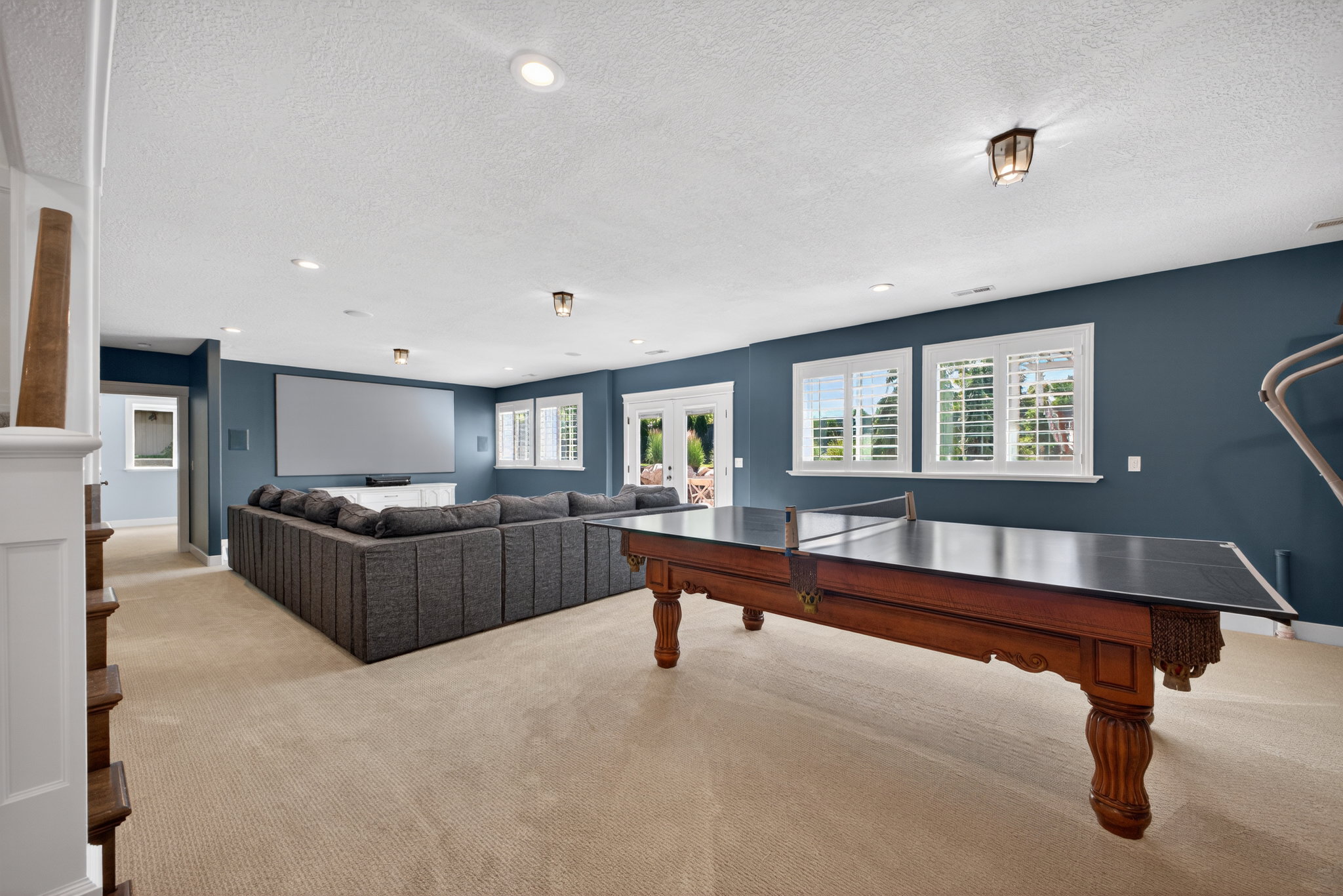 Spacious recreation room featuring recessed lighting, a large projection screen, and durable carpeting