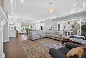 Open-concept living area featuring wood-finish flooring, recessed lighting, and ornate chandeliers