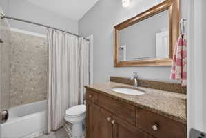 Bathroom featuring a wood-finish vanity with a stone countertop and an undermount sink
