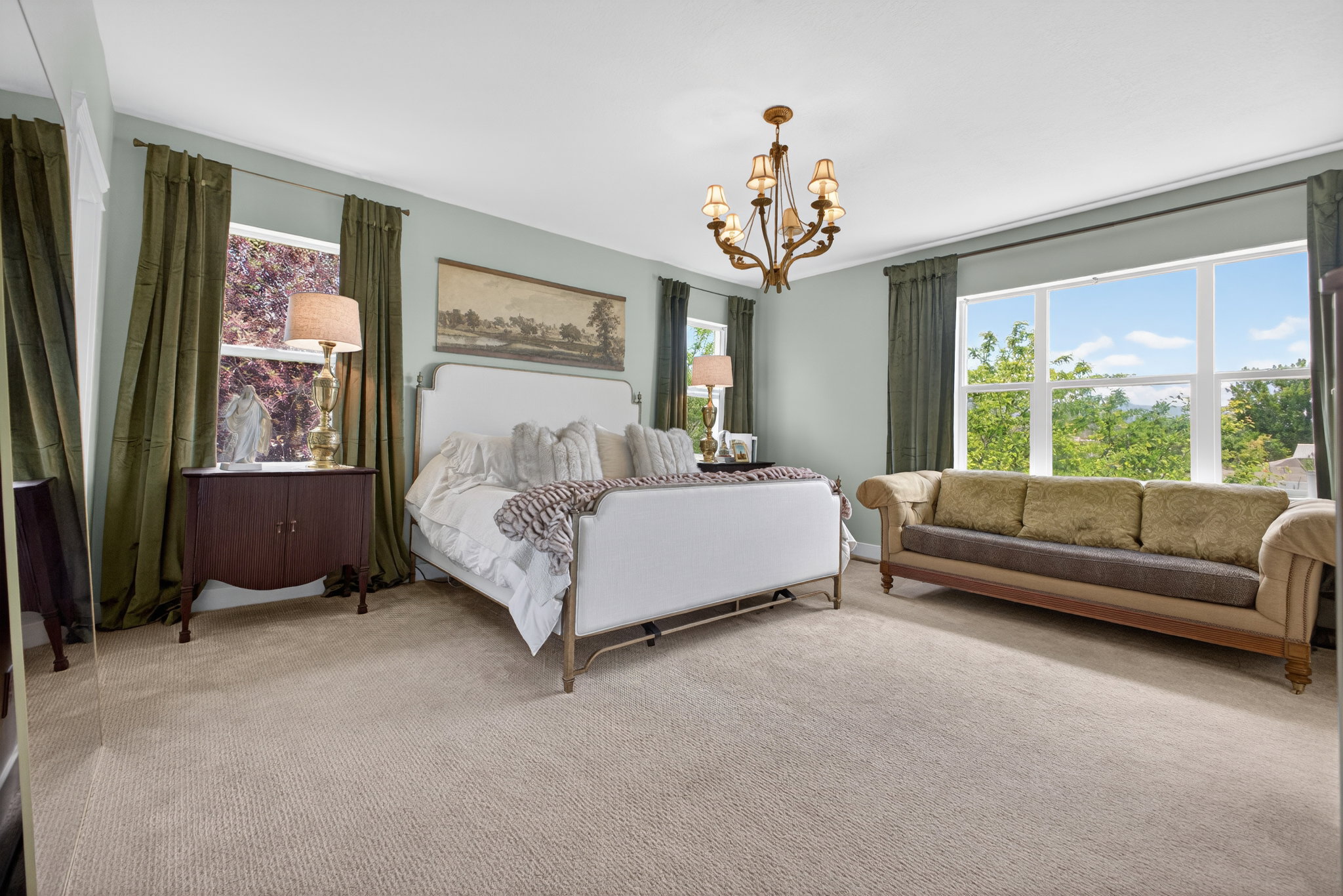 Spacious room featuring broadloom carpeting, light blue wall paint, and a multi-pane window overlooking trees