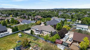 Expansive property featuring a multi-story residence with a covered balcony, mature trees, and a spacious paved area